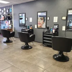 Inside view of salon, with chairs lined along a wall of workstations with lighted mirrors